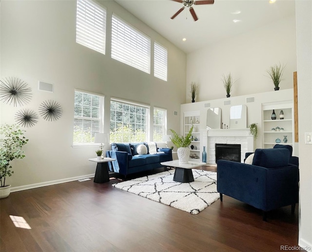 living room featuring dark hardwood / wood-style floors, ceiling fan, and a towering ceiling