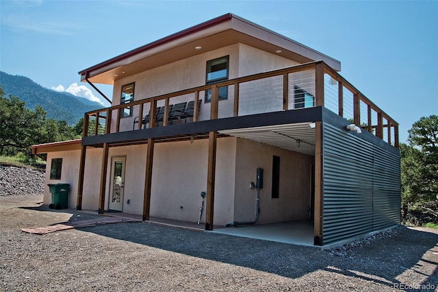 back of house featuring a mountain view and a balcony