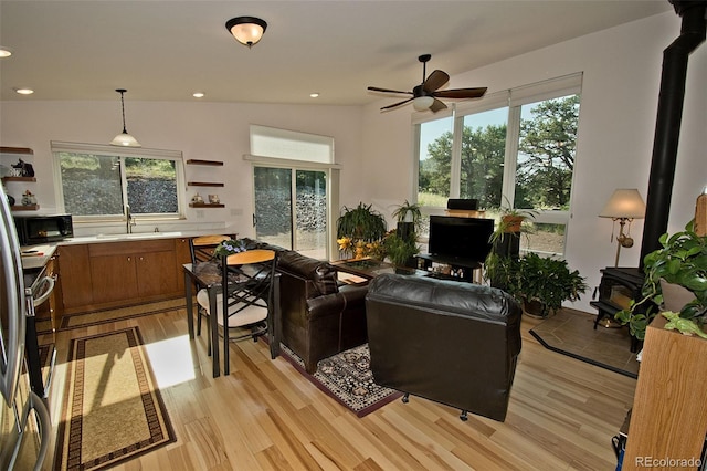 living room featuring lofted ceiling, ceiling fan, light wood-type flooring, and sink