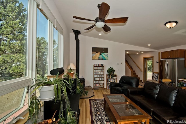 living room featuring light hardwood / wood-style floors, vaulted ceiling, and ceiling fan