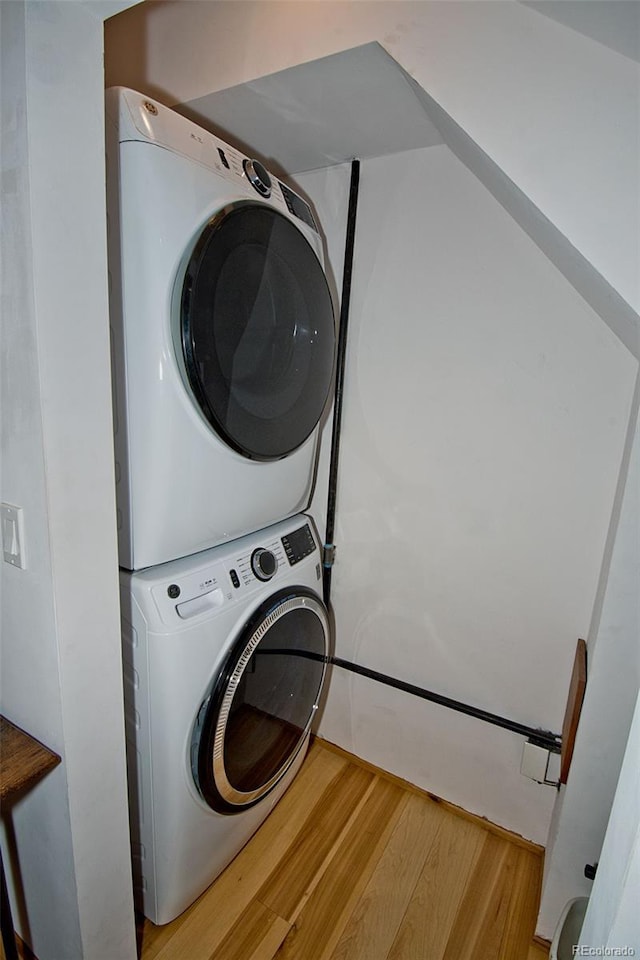 washroom featuring stacked washer / dryer and wood-type flooring