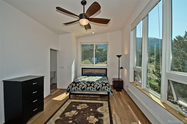 bedroom with light hardwood / wood-style flooring, vaulted ceiling, and ceiling fan