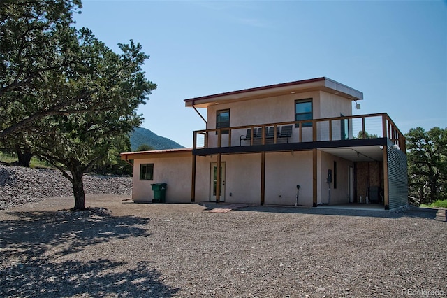 rear view of property with a mountain view and a balcony