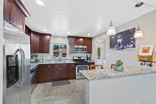 kitchen with sink, appliances with stainless steel finishes, hanging light fixtures, light stone counters, and kitchen peninsula