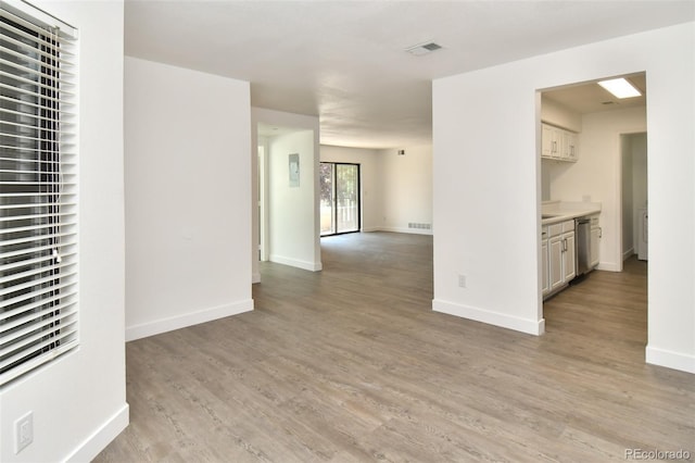 spare room with light wood-style floors, visible vents, and baseboards