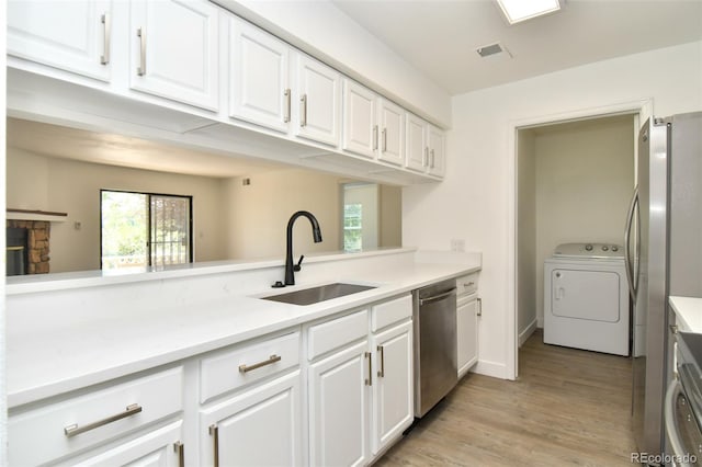 kitchen featuring stainless steel appliances, washer / clothes dryer, visible vents, white cabinets, and a sink