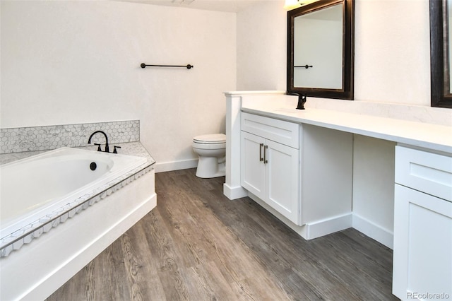 full bath featuring a garden tub, toilet, vanity, wood finished floors, and baseboards