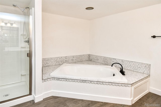 full bathroom with a bath, a shower stall, baseboards, and wood finished floors