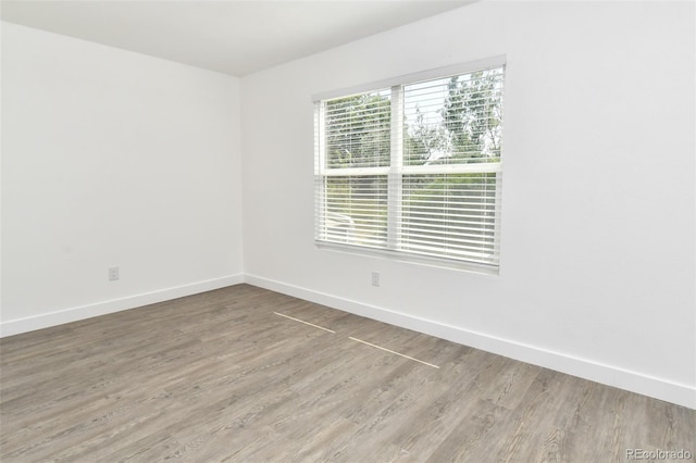 spare room featuring baseboards and wood finished floors