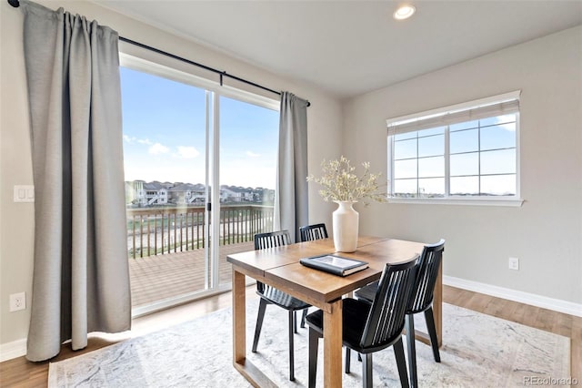 dining room featuring baseboards, recessed lighting, a water view, and wood finished floors