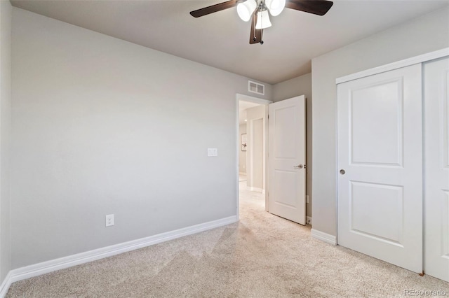 unfurnished bedroom featuring a ceiling fan, light colored carpet, visible vents, baseboards, and a closet