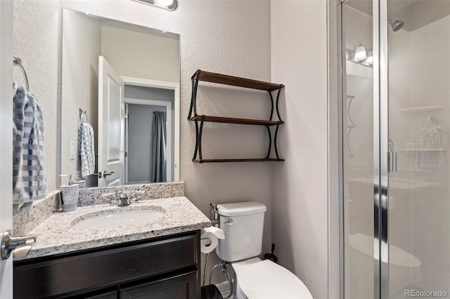 full bath with vanity, toilet, a textured wall, and a stall shower