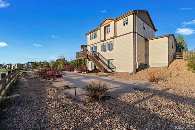rear view of property with stairs, fence, and a deck