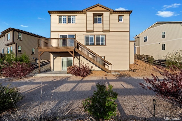 back of property featuring a deck, fence, and stairs