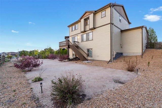 rear view of house featuring stairs, a wooden deck, and fence