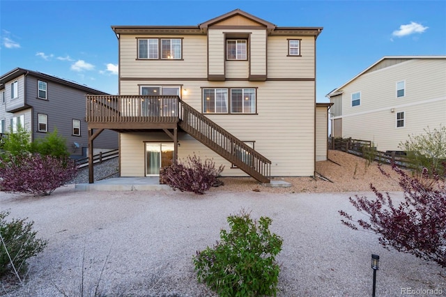 back of house featuring stairway, a deck, and fence
