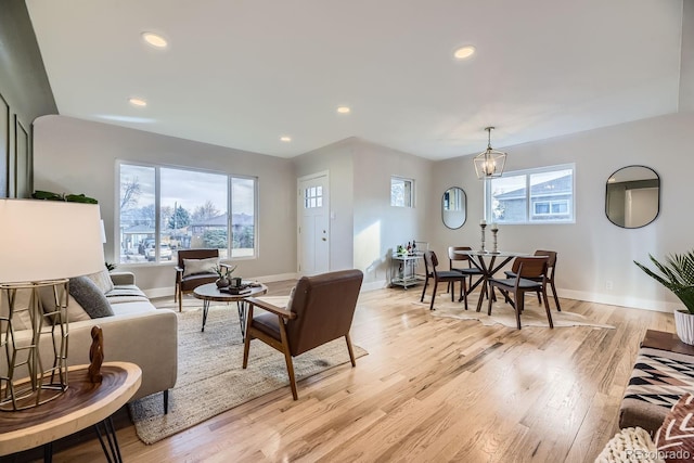 living room featuring light hardwood / wood-style flooring, plenty of natural light, and an inviting chandelier