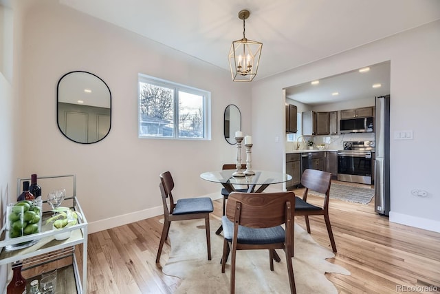 dining room with light hardwood / wood-style flooring, a chandelier, and sink