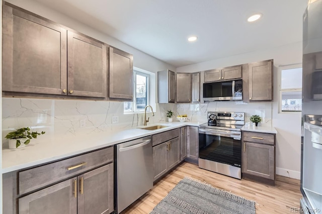 kitchen with decorative backsplash, light hardwood / wood-style floors, sink, and appliances with stainless steel finishes