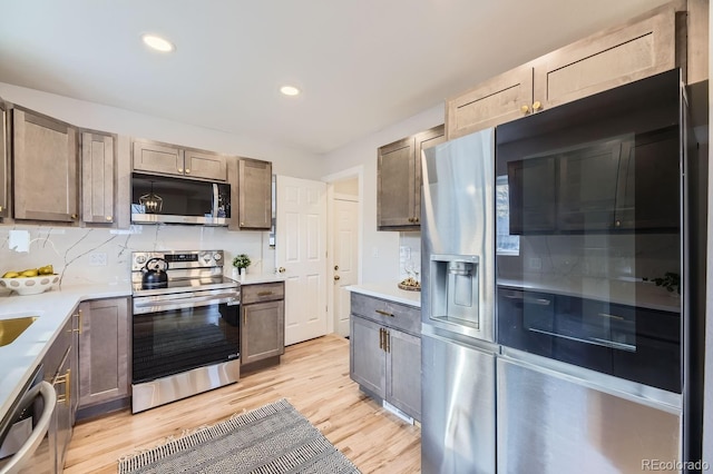 kitchen featuring backsplash, stainless steel appliances, and light hardwood / wood-style flooring