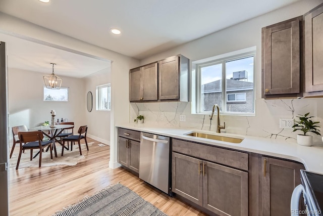 kitchen featuring dishwasher, sink, hanging light fixtures, dark brown cabinets, and a chandelier