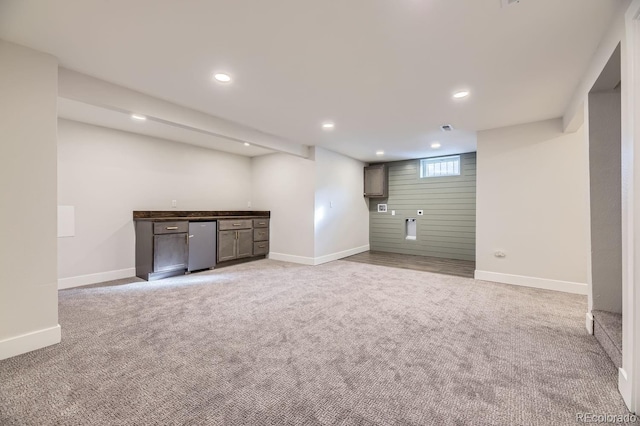 basement featuring wooden walls and light colored carpet