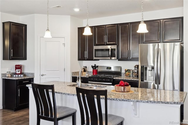 kitchen with a breakfast bar, a sink, appliances with stainless steel finishes, dark wood-style floors, and pendant lighting