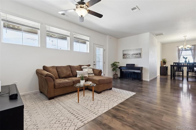 living area with dark wood-type flooring, visible vents, baseboards, and ceiling fan with notable chandelier