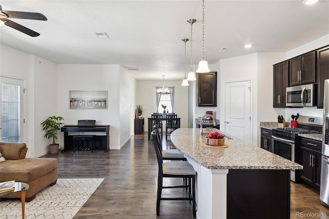 kitchen with dark wood finished floors, open floor plan, stainless steel appliances, dark brown cabinets, and a sink