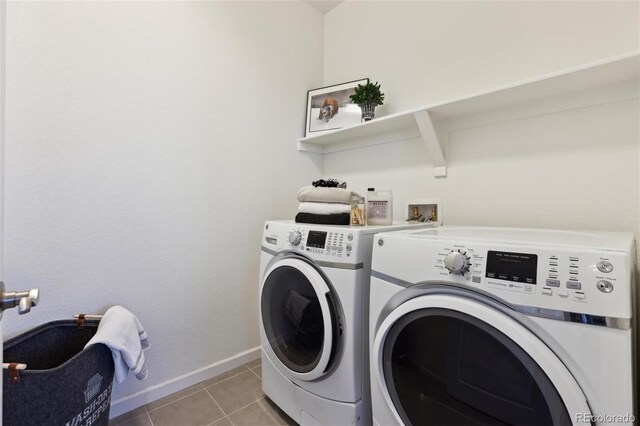 laundry area featuring light tile patterned floors, laundry area, washer and clothes dryer, and baseboards