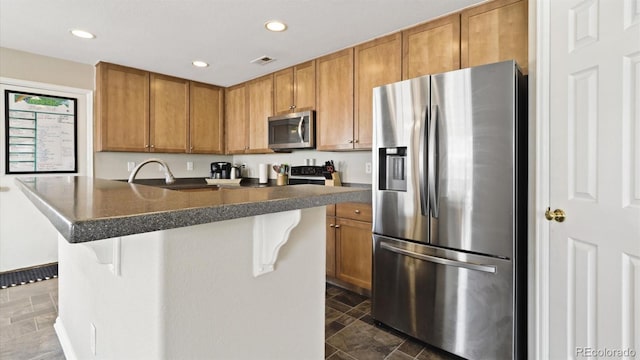 kitchen with a kitchen bar, dark tile patterned floors, and appliances with stainless steel finishes