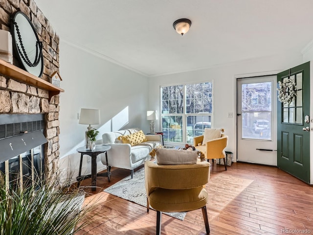 living room featuring a stone fireplace, crown molding, and hardwood / wood-style flooring