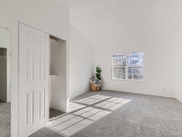 carpeted spare room featuring vaulted ceiling