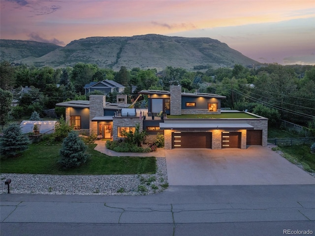 view of front of home with a mountain view, a garage, and a yard