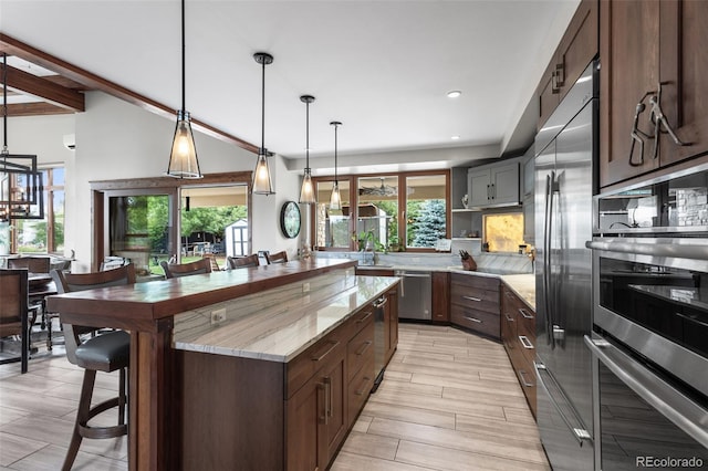 kitchen featuring light stone countertops, appliances with stainless steel finishes, plenty of natural light, and hanging light fixtures