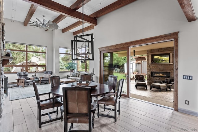 dining area with beamed ceiling, a fireplace, and ceiling fan