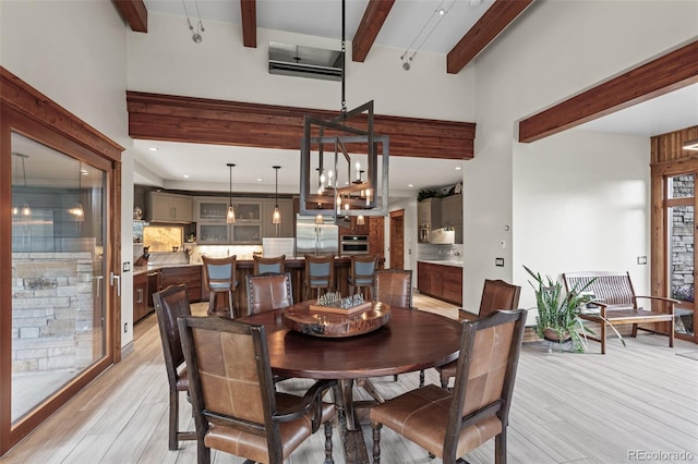 dining area featuring beamed ceiling, light wood-type flooring, and a wall unit AC