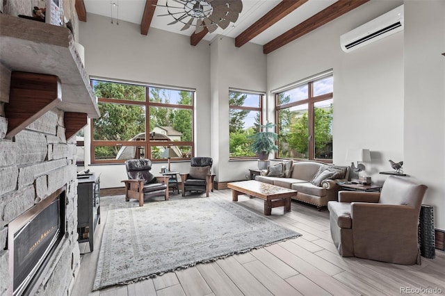 interior space with a high ceiling, an AC wall unit, ceiling fan, a fireplace, and beamed ceiling