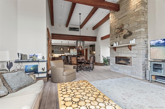 living room featuring a fireplace, beamed ceiling, a high ceiling, and hardwood / wood-style flooring