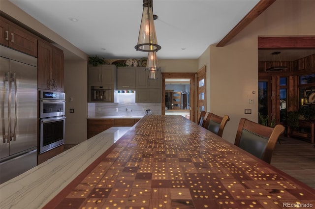 kitchen with beamed ceiling, decorative light fixtures, and appliances with stainless steel finishes