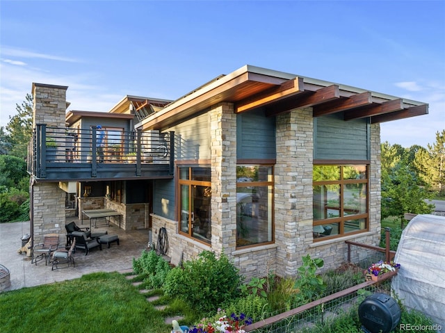 rear view of property featuring a balcony and a patio