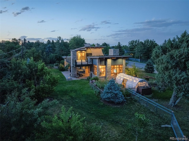 back house at dusk with an outbuilding, a yard, and a patio