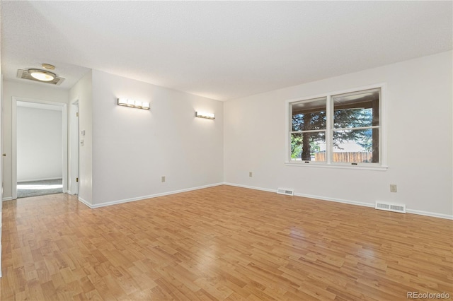 empty room featuring a textured ceiling and light hardwood / wood-style flooring