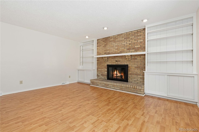 unfurnished living room featuring light hardwood / wood-style flooring, a textured ceiling, and a fireplace