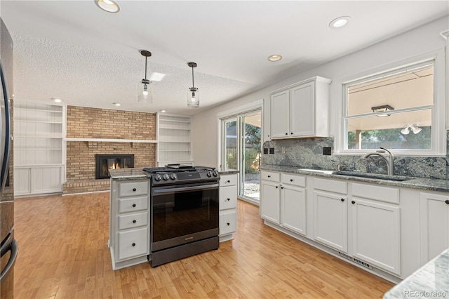 kitchen with black gas range, sink, decorative light fixtures, white cabinetry, and a textured ceiling