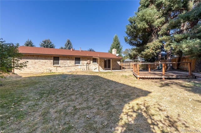 back of property with a deck and a lawn