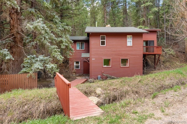back of property with fence, a chimney, and roof with shingles