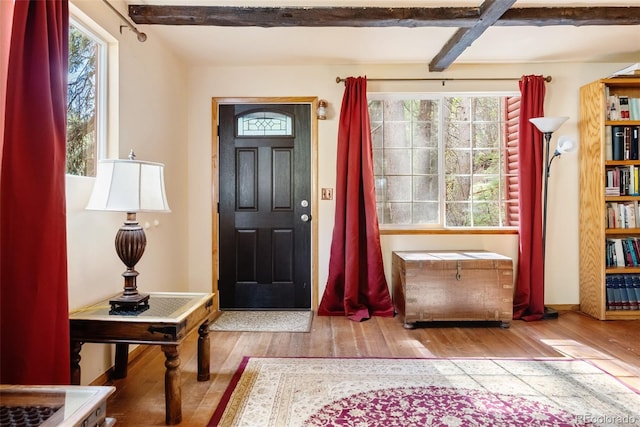 foyer entrance with baseboards, beam ceiling, hardwood / wood-style floors, and a wealth of natural light