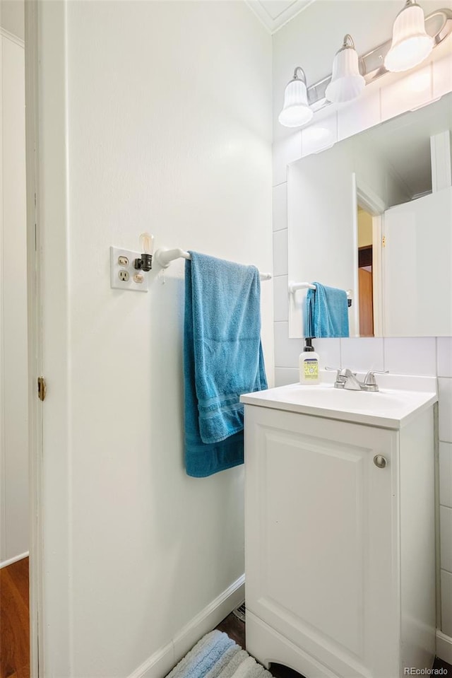 bathroom with crown molding, vanity, baseboards, and wood finished floors