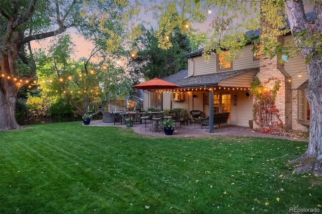 back house at dusk with a yard and a patio